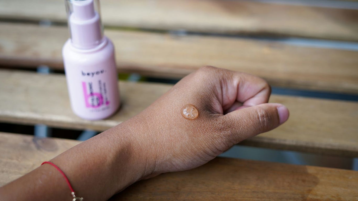 a woman's hand holding a bottle of sunscreen on a wooden bench