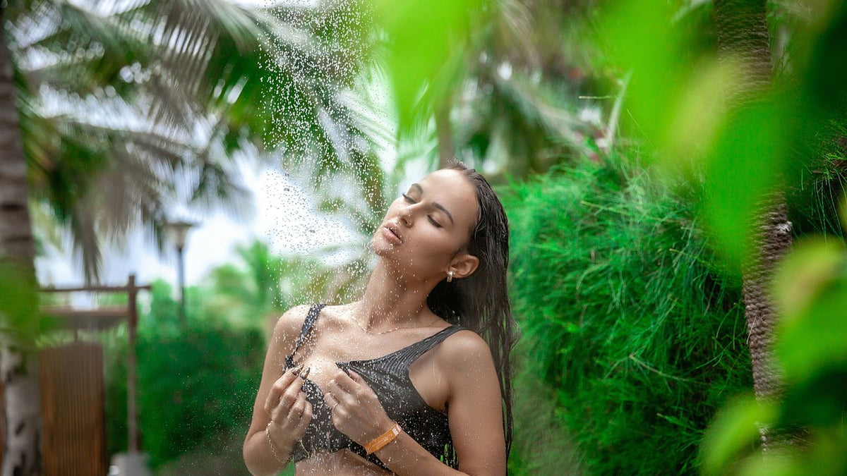 Woman showering outdoors surrounded by lush greenery