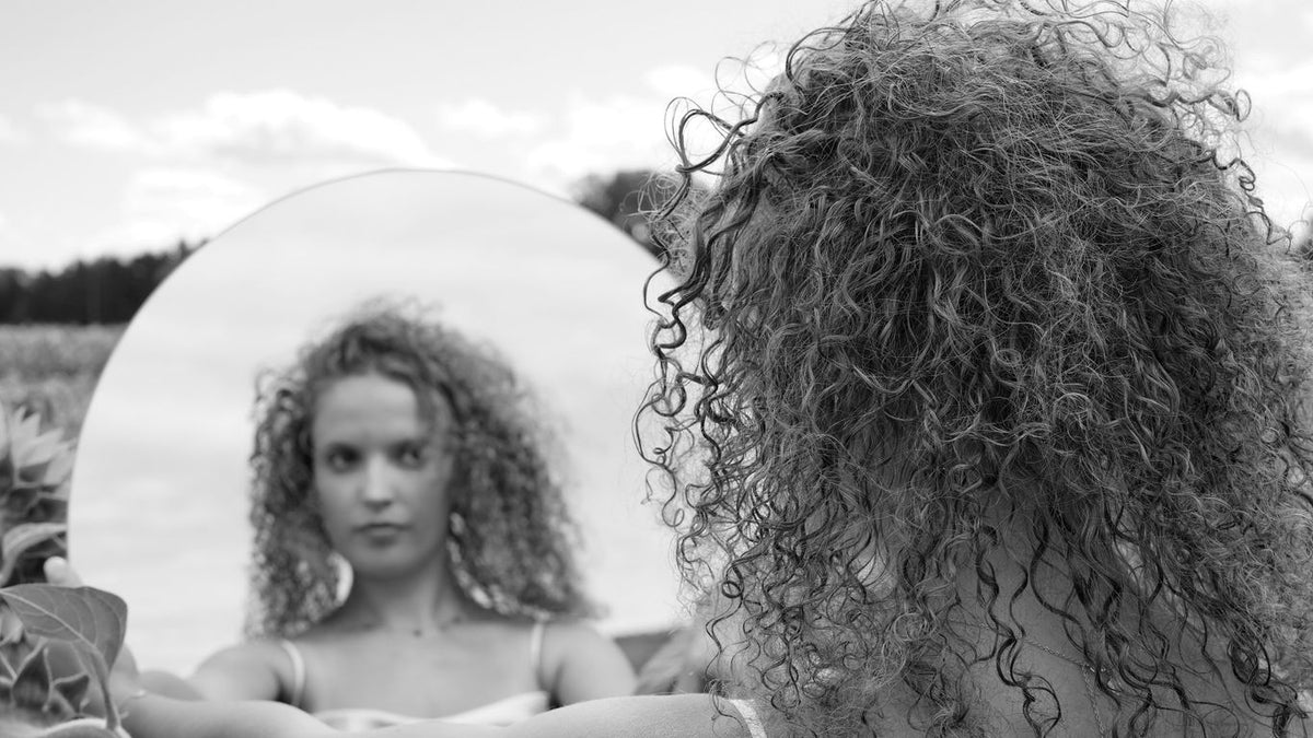 a woman with curly hair looking in a mirror